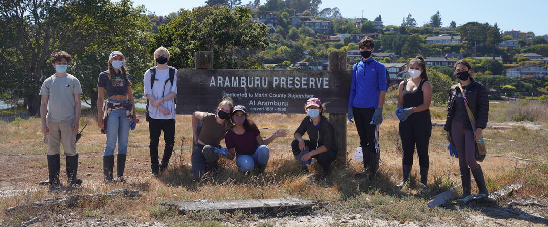 Volunteers Standing at Aramburu Island Sign